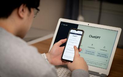 Person using a chatbot on their mobile phone and laptop