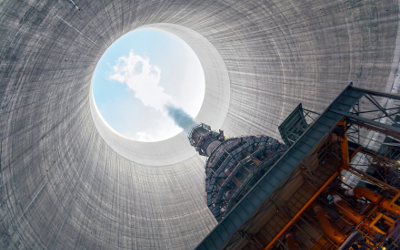 View of looking up a chimney of a thermal power plant, with smoke and blue sky at the top