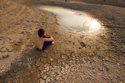 Child sitting on cracked earth