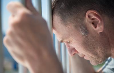 Male inmate holding prison bars