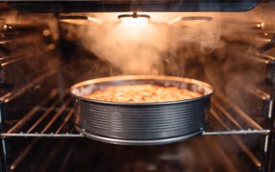 Close up of a cake in a metal tin sitting on a rack inside an oven