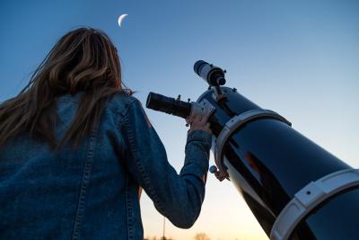 Girl looking at moon through telescope