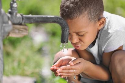 Shutterstock-722925454 Young child drinking water from an outdoors tap