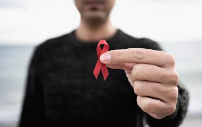 Man holding red AIDS awareness ribbon
