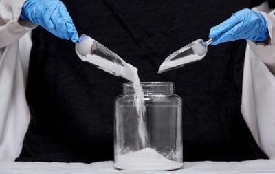 People pouring powders into a glass jar