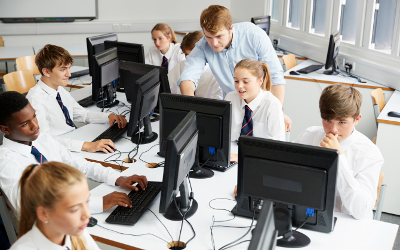 Teenage school children wearing white shirts and ties, in a classroom with a teacher and computer monitors