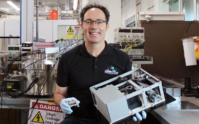 Simeon Barber, sitting in a laboratory, holding a piece of equipment