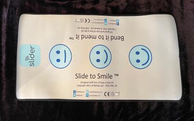 The slider, a rectangular white mat with the words 'Slide to Smile' and three blue smiley faces printed on it