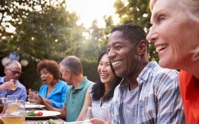 A diverse group of men and women sitting round a table outside whilst eating