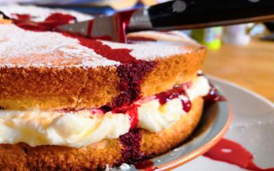 Victoria Sponge cake with a knife curring through it