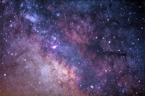 The bright lights and pink and purple swirls of starts and galaxies  against a black background