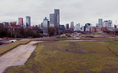 A green field with high-rise buildings in the distance