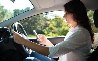 Woman driving whilst looking at her mobile phone