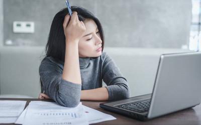 Woman sitting at a table with papers and a laptop on it