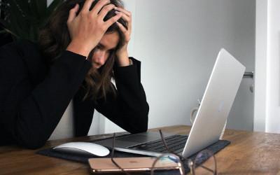 Woman with her head in her hands, looking at a laptop
